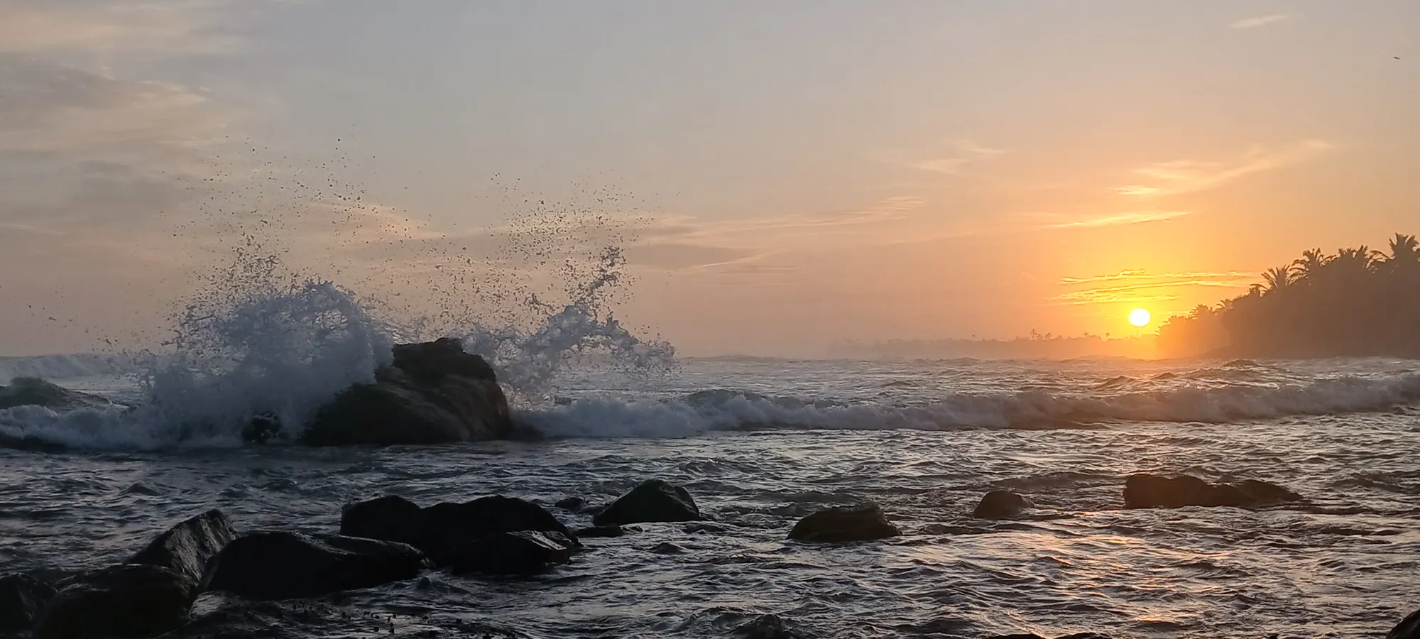 Waves breaking over rocks at sunset
